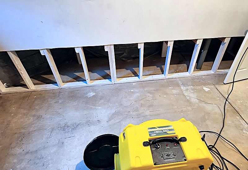 Yellow CleanShield HEPA 550 air scrubber on a concrete floor in front of a flood-cut wall with exposed wooden studs